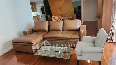Spacious living room with modern leather sofa and elegant armchair on polished wooden floor.