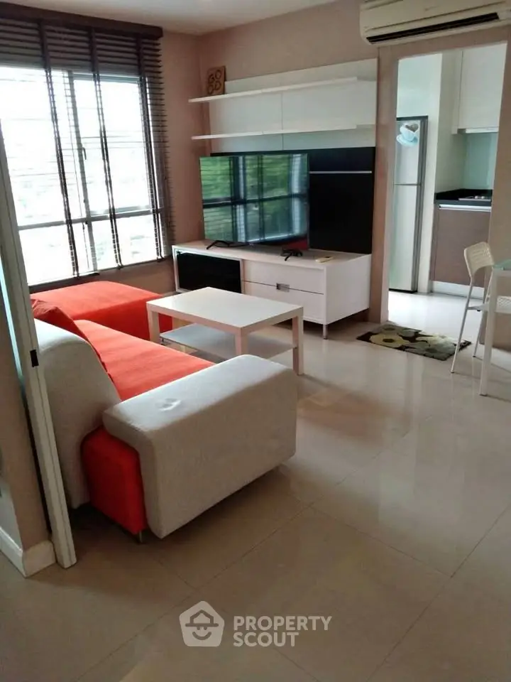Modern living room with bright sofa, sleek TV unit, and large windows for natural light.