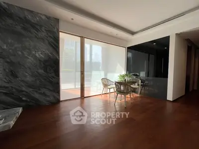 Elegant modern living room with wooden flooring and stylish furniture, featuring large windows for natural light.