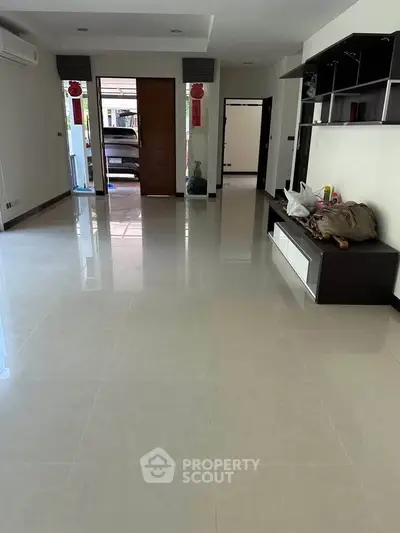 Spacious modern living room with glossy tile flooring and built-in shelving.
