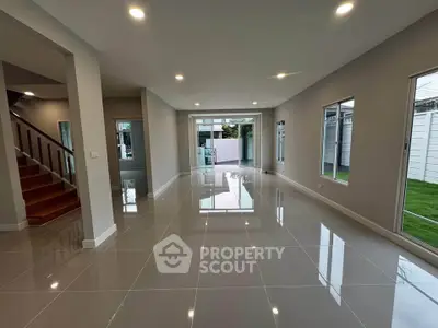 Spacious modern living room with glossy tiled floors and ample natural light.