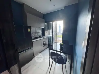 Modern kitchen with sleek design and city view, featuring compact dining area and large window.