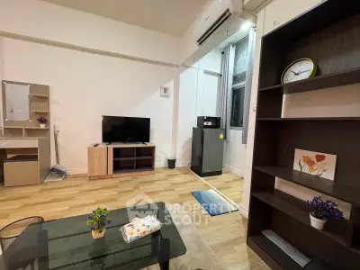Cozy living room with modern furniture and wooden flooring, featuring a TV and air conditioning.