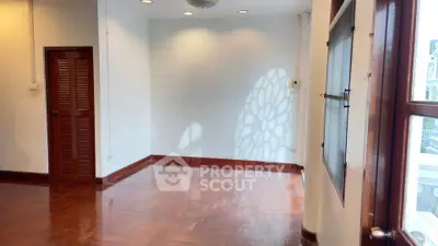 Spacious empty room with wooden floors and large windows, perfect for customization.