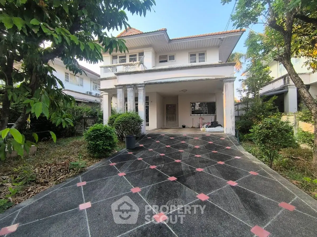 Charming two-story house with spacious driveway and lush greenery, perfect for family living.