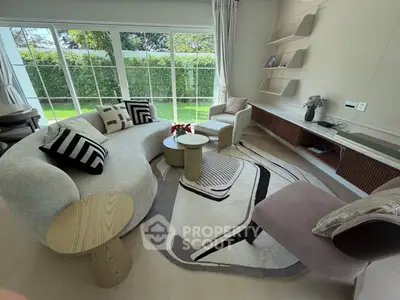 Luxurious living room with modern furniture and large windows overlooking a lush garden.