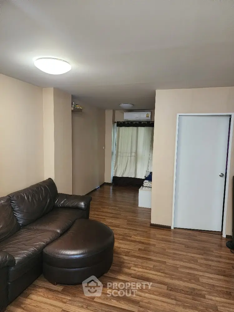 Spacious living room with glossy hardwood flooring and comfortable leather sectional sofa, ideal for family relaxation and entertaining guests.