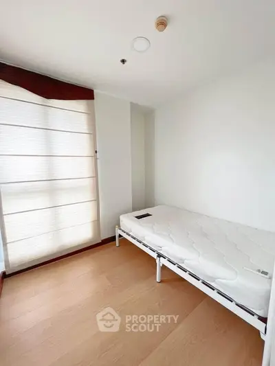 Minimalist bedroom with single bed and large window, perfect for cozy living.