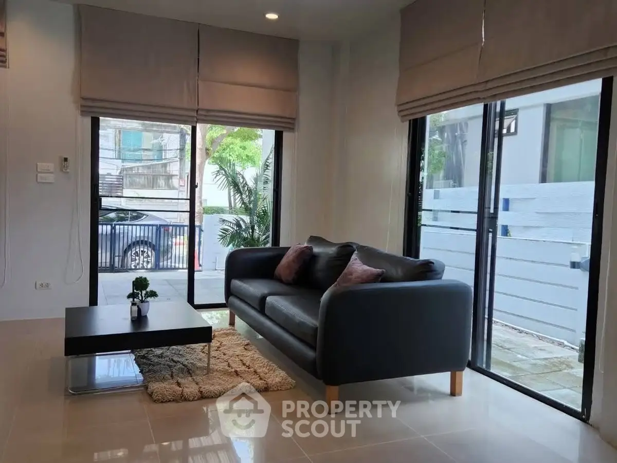 Modern living room with sleek sofa and large windows offering natural light