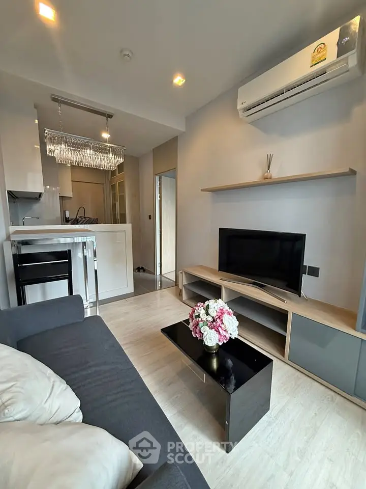 Modern living room with sleek furniture and open kitchen layout, featuring a cozy ambiance and stylish decor.