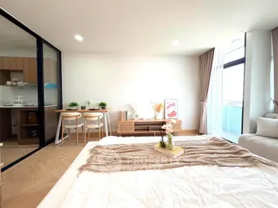 Modern bedroom with open layout and stylish decor, featuring a cozy bed and dining area with natural light.