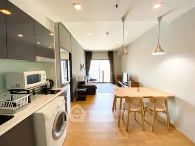 Modern open-layout living room with kitchen, featuring wooden flooring and contemporary furniture.