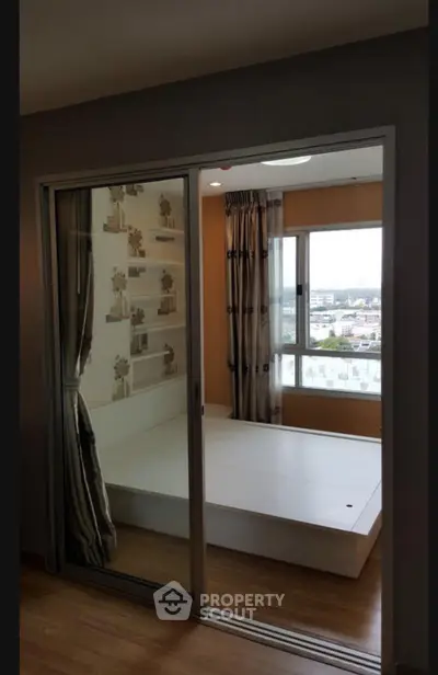 Modern bedroom with sliding glass doors and city view, featuring stylish decor and natural light.
