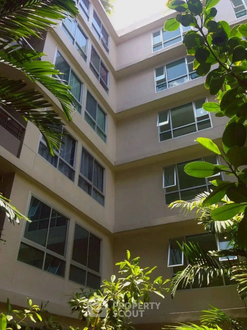 Modern apartment building exterior with lush greenery and large windows