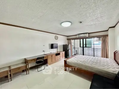 Spacious studio apartment with modern furnishings and large windows for natural light.