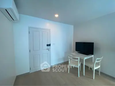 Modern minimalist living room with TV and dining set, featuring sleek white furniture and air conditioning.
