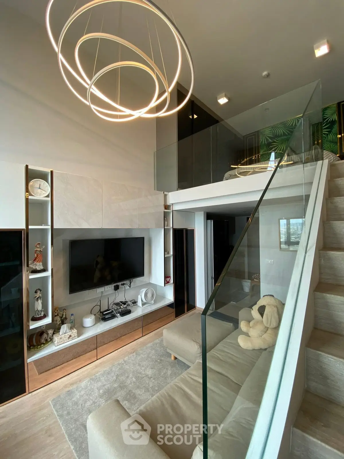 Modern living room with loft, stylish lighting, and glass staircase