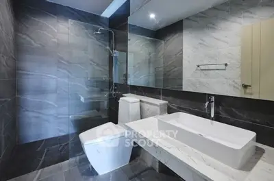 Modern bathroom with sleek design, featuring a large mirror and elegant fixtures.