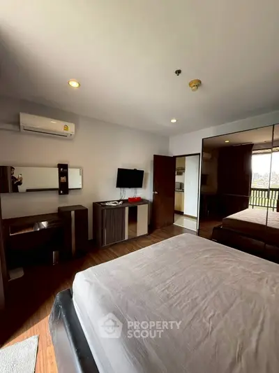Spacious bedroom with modern furnishings and large mirrored wardrobe