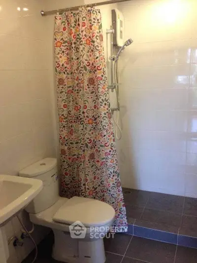 Cozy bathroom with floral shower curtain and modern fixtures in a bright, tiled space.