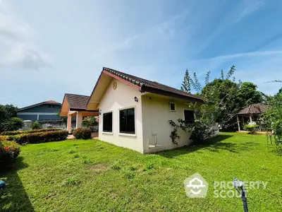 Charming single-story home with lush garden and spacious lawn under clear blue sky.