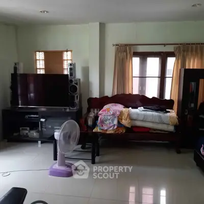 Cozy living room with TV, fan, and comfortable seating area.