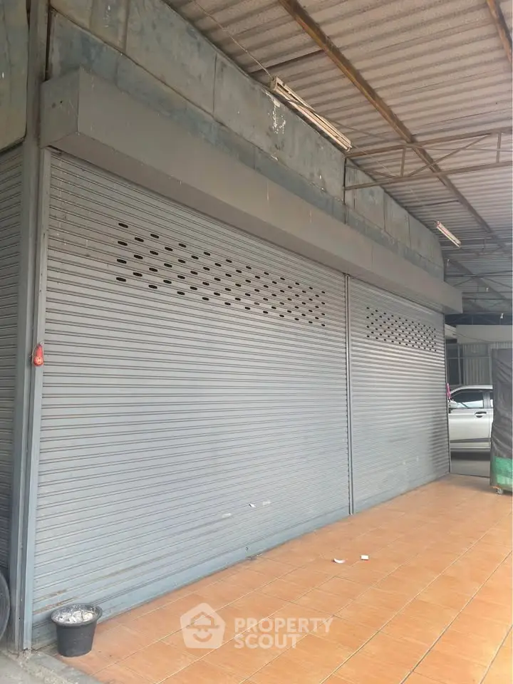 Commercial property with closed metal shutters and tiled flooring, ideal for business setup.