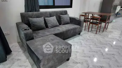 Modern living room with sleek gray sofa and dining area