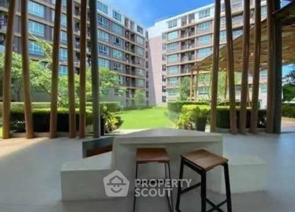 Modern apartment complex with lush garden view and stylish outdoor seating area.