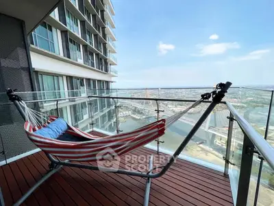 Stunning high-rise balcony with hammock and panoramic city river view.