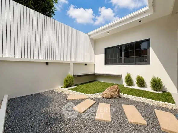 Modern minimalist garden with stone pathway and sleek white fence