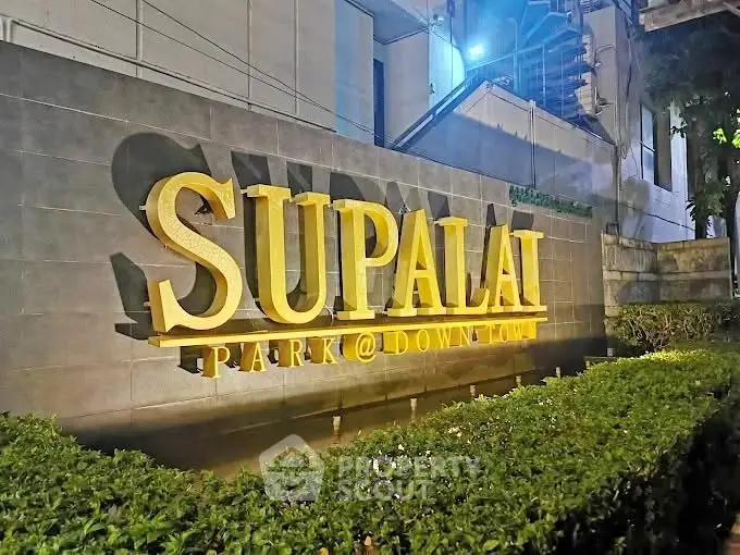 Supalai Park Downtown entrance sign with lush greenery at night