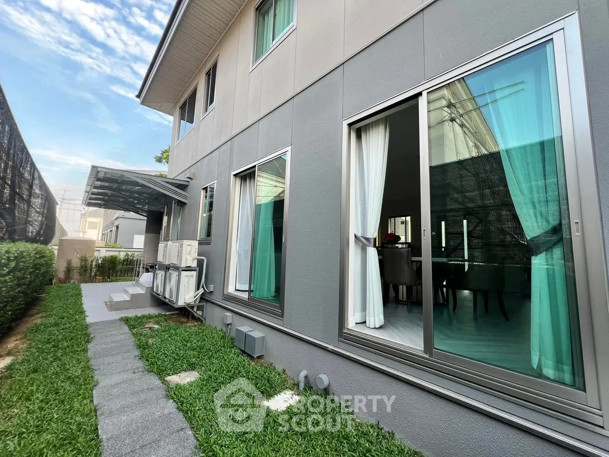 Modern two-story home with large windows and lush green lawn, showcasing contemporary architecture and inviting interiors.
