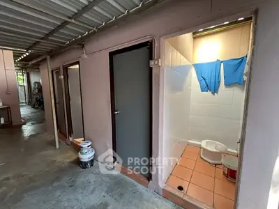 Simple outdoor bathroom with tiled floor and clothes drying, basic setup.