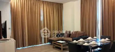 Elegant living room with cozy sofa and dining area, featuring floor-to-ceiling curtains for a warm ambiance.