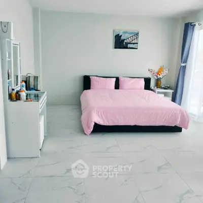 Spacious bedroom with modern decor and large windows offering natural light.