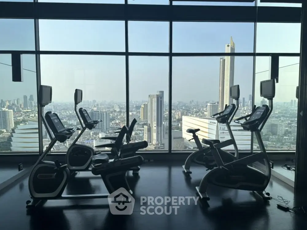 Luxurious gym with panoramic city view and modern exercise equipment.