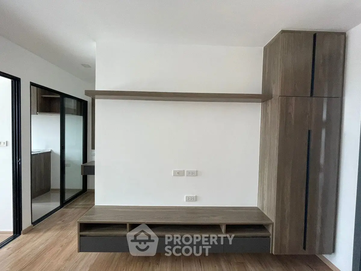 Modern minimalist living room with sleek wooden cabinetry and open layout.