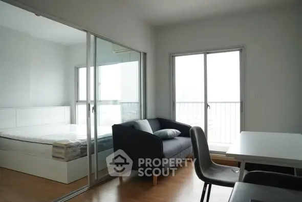 Modern apartment interior with cozy living room and bedroom separated by glass doors.