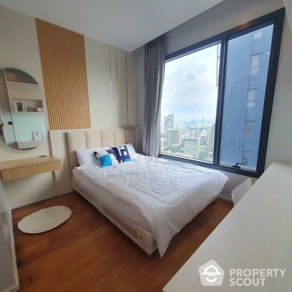 Modern bedroom with city view, stylish decor, and large window for natural light.