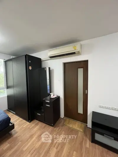 Modern bedroom with sleek black furniture and air conditioning unit