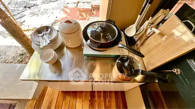 Modern kitchen setup with stainless steel countertop, cookware, and utensils in a cozy outdoor setting.