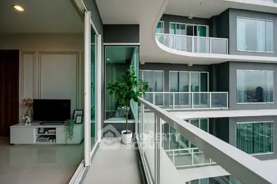 Modern apartment with spacious balcony and city view, featuring sleek glass railings and stylish interior.