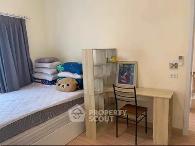 Cozy bedroom with study area, featuring a comfortable bed and a compact desk with shelving.