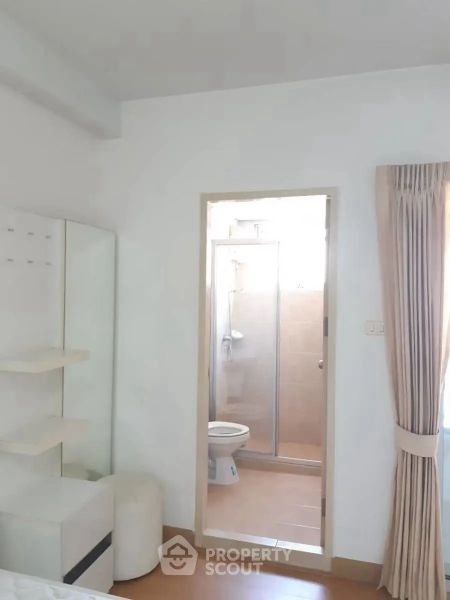 Bright bedroom with ensuite bathroom featuring glass shower door and modern decor.