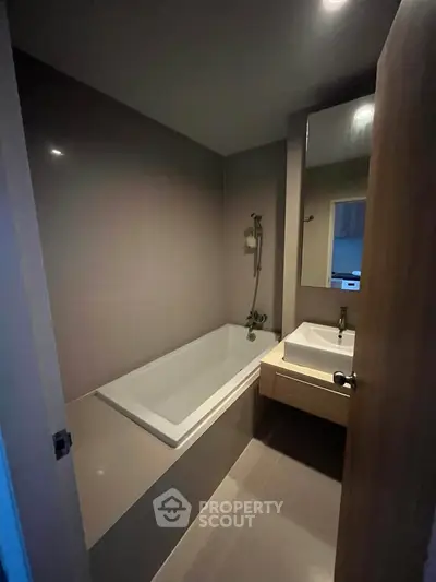 Modern bathroom with sleek bathtub and stylish sink in a cozy apartment.