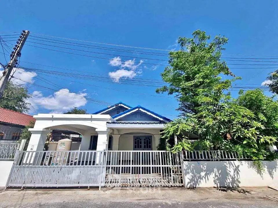 Charming single-story house with blue roof and gated entrance in a serene neighborhood.