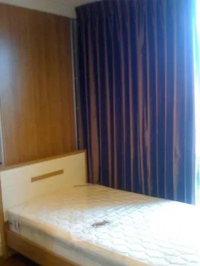 Cozy bedroom with single bed and elegant curtains, perfect for a peaceful retreat.