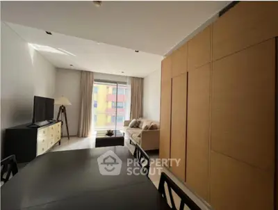 Modern living room with stylish furniture and large window offering natural light.