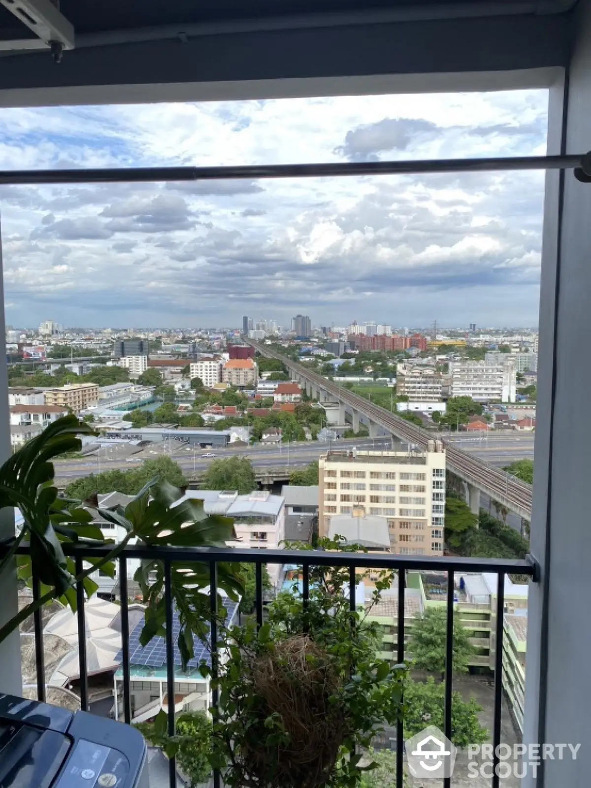 Stunning cityscape view from a high-rise balcony with lush greenery and expansive skyline.